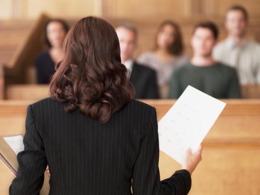 lawyer holding document and speaking to jury in courtroom